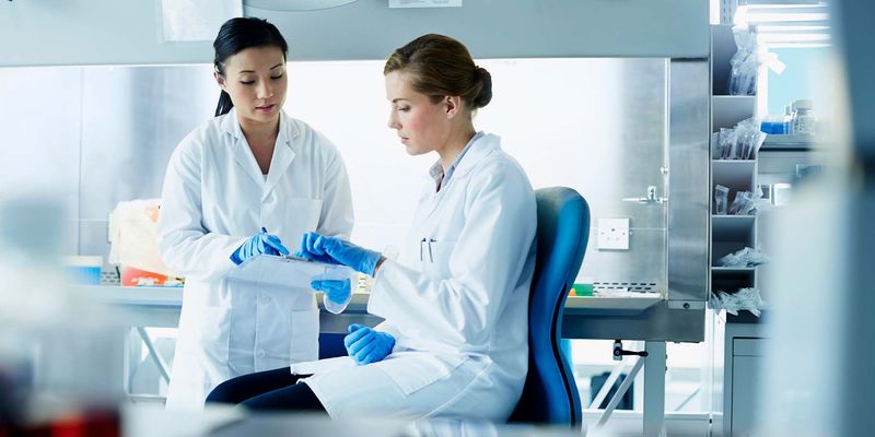Female life scientists talking beside biological safety cabinet