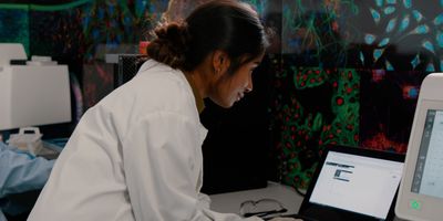 Female scientist in life science lab looking over data on laptop
