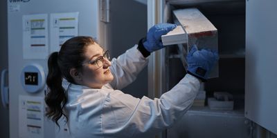 Female scientist pulls sample off rack in an ultra-low temperature freezer